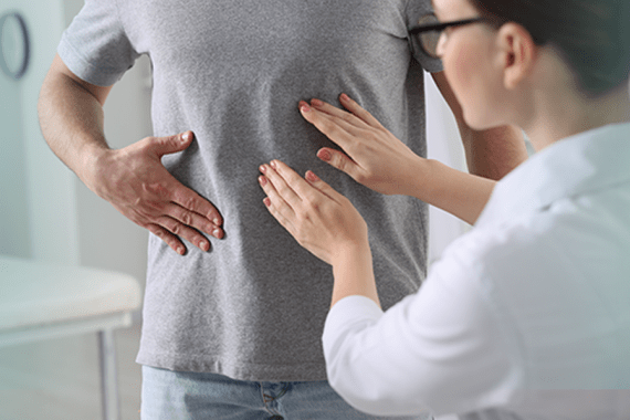 A doctor wearing a white coat feels the abdomen of a men who is also touching his abdomen